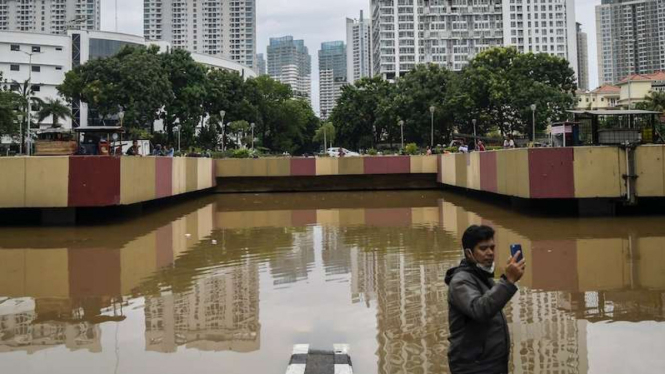 Warga berswafoto saat banjir menutup underpass di jalan Kota Baru Bandar Kemayoran Jakarta, Jumat (24/1/2020). Banjir dikawasan tersebut diakibatkan intensitas hujan yang tinggi dan drainase yang buruk. 
