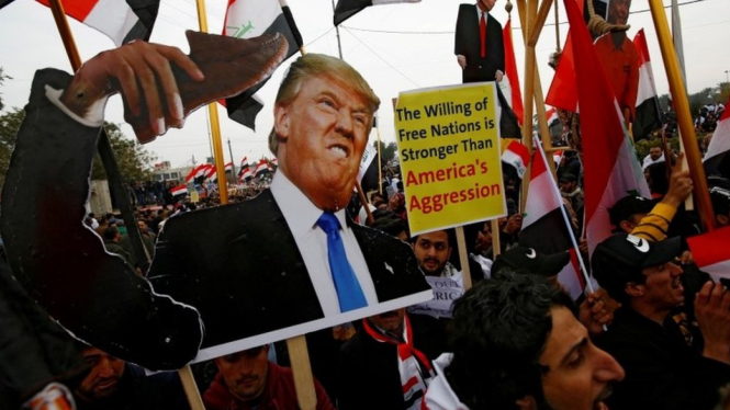 Para pendukung ulama Syiah Irak, Moqtada al-Sadr, membawa poster bergambar Donald Trump. - Reuters