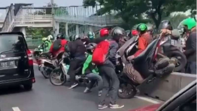 Pemotor gotong royong mengangkat sepeda motor keluar dari jalur busway