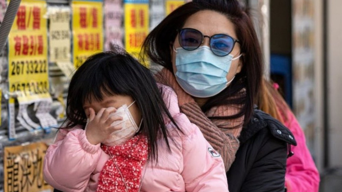 Seorang perempuan warga Hong Kong dan anaknya mengenakan masker saat berjalan di pusat keramaian. - Yat Kai Yeung/Getty Images