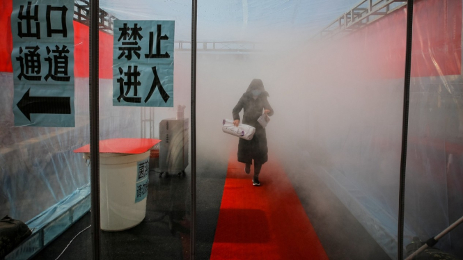 eorang wanita tengah di semprot desinfekta dipintu masuk komplek Perumahan di Tianjin (Image Credit: China News Service)