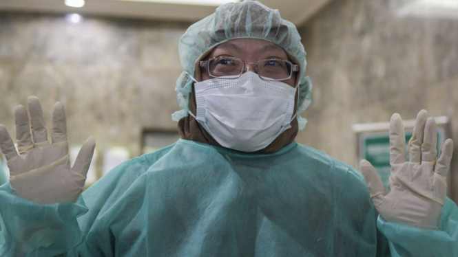 Vivi Setyawati, kepala pusat penelitian biomedis di Badan Penelitian dan Pengembangan Kesehatan, mengenakan pakaian pelindung dan masker sebelum masuk ke laboratorium pengujian virus Corona. - GALIH PRADIPTA/Antarafoto