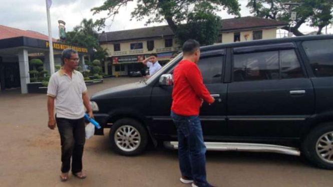 Tersangka penganiayaan kucing (bawa map biru) diperiksa polisi.