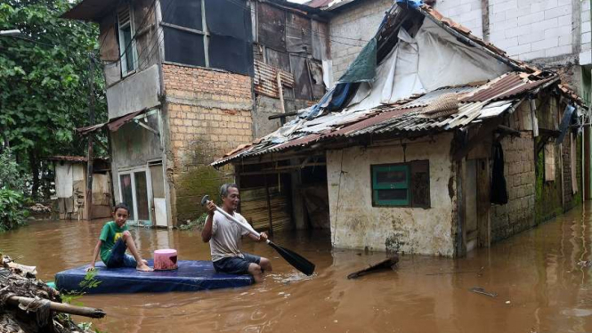 Warga menggunakan perahu akibat banjir luapan Sungai Ciliwung di Cawang 