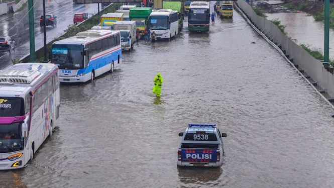 Petugas polisi tengah mengatur kendaraan di Tol Jakarta-Cikampek yang banjir di Jatibening Bekasi, Jawa Barat, Selasa (25/2/2020).