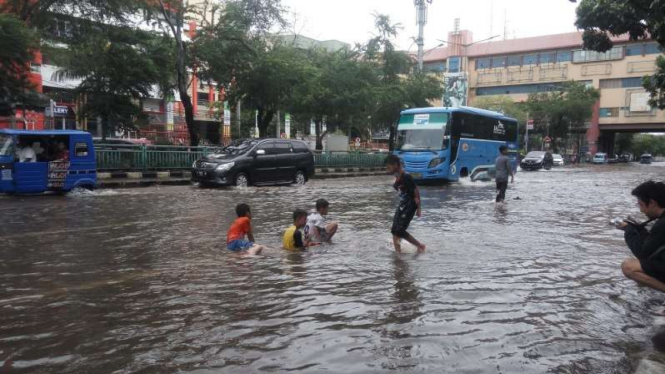 Anak-anak di Mangga Dua, Jakarta Barat, bermain-main di genangan banjir.
