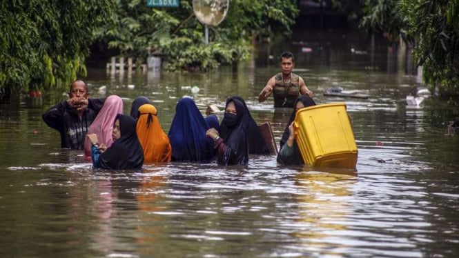 Sejumlah warga melintasi genangan banjir di Perumahan Jatibening Permai, Bekasi