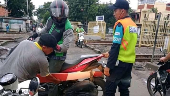 Palang perlintasan kereta masuk ke sela motor