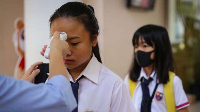 Siswa menjalani pemeriksaan suhu tubuh sebelum sekolah diliburkan. 