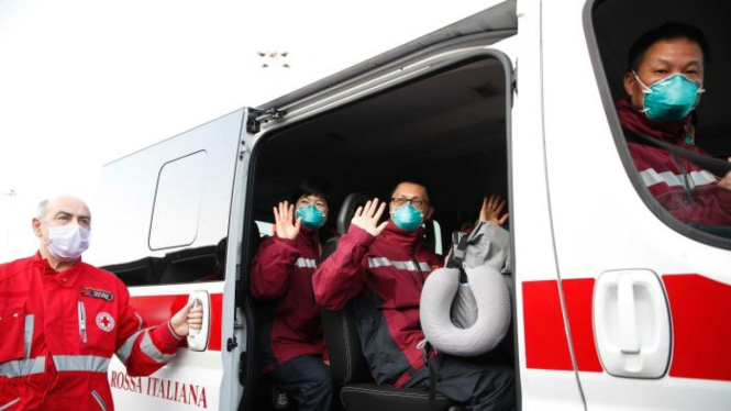 Petugas medis dan paramedis dari Tiongkok memberi hormat setelah tiba di bandara Malpensa di Milan, Rabu, 18 Maret 2020.