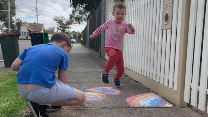 Max, menggambar pelangi yang dilihat oleh adiknya, Lenny, di kawasan Essendon, Melbourne.