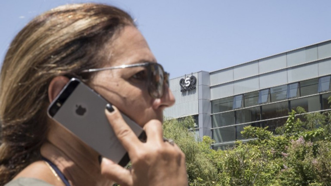 Seseorang sedang menelepon pakai iPhone depan kantor NSO Group di Israel.