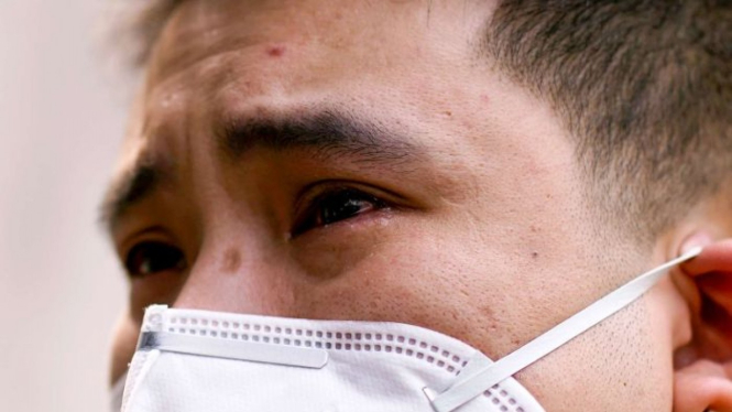 Seorang warga China menitikkan air matanya saat ada peringatan mengenang mereka yang meninggal akibat wabah virus corona.