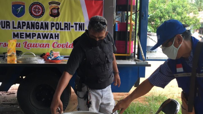 Para anggota komunitas Mempawah sedang memasak makanan di dapur lapangan