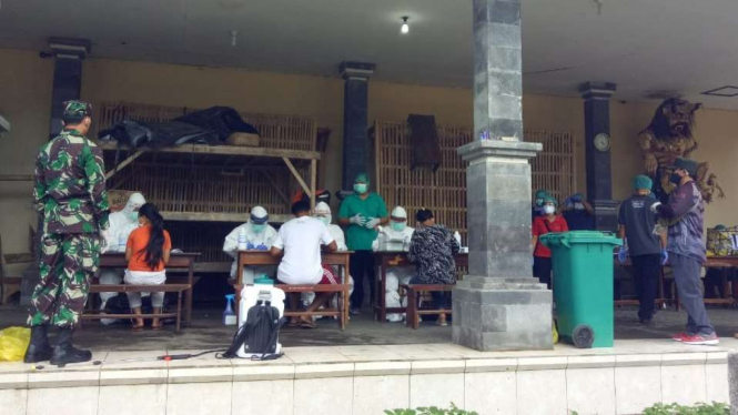 Aparat TNI menjaga dan mengawasi warga saat menjalani pemeriksaan secara cepat (rapid test) untuk mengetahui terjangkit corona atau tidak di satu kampung di Kabupaten Bangli, Bali, Kamis, 30 April 2020.