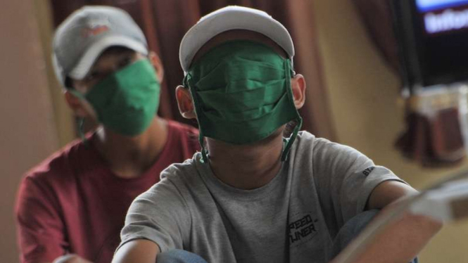 Sejumlah warga yang terjaring razia masker diberikan edukasi melalui tayangan informasi terkait COVID-19 , di Asrama PGRI Plaju Palembang, Sumsel, Selasa (19/5/2020). 