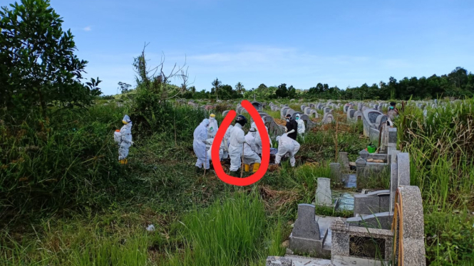Kapolsek Sungai Pinyuh, Kompol M.Pangaribuan mengenakan APD dan Helm hitam membantu memasukan peti jenazah ke liang lahat PDP (Dian S/Suarakalbar.co.id)