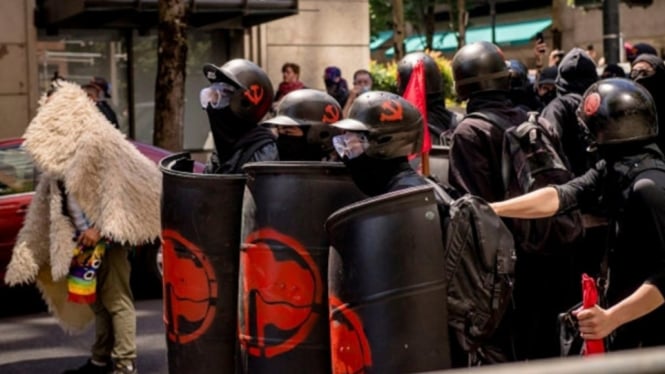 Pengunjung rasa dengan simbol Antifa di perisai mereka. 