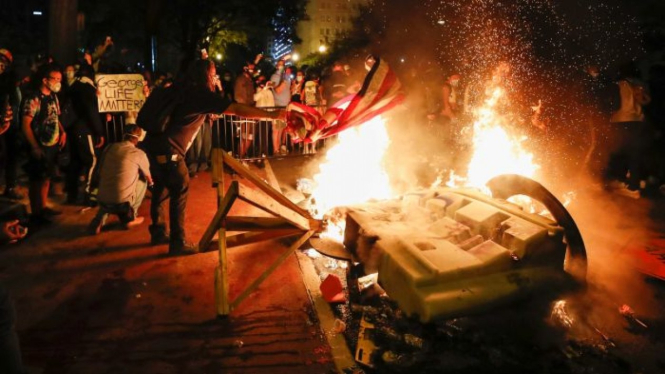Para pengunjuk rasa membakar bendera Amerika untuk memprotes kematian George Floyd di dekat Gedung Putih di Washington.