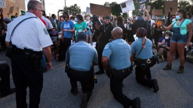 Polisi di New York berlutut di hadapan demonstran. 