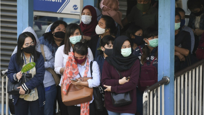 Calon penumpang mengantre untuk menaiki bus Transjakarta di Halte Harmoni