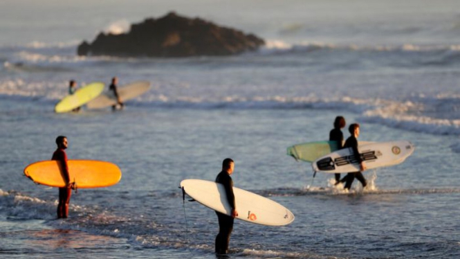 Warga kembali berselancar di salah satu pantai Christchurch setelah Selandia Baru mencabut semua aturan pembatasan terkait virus corona.