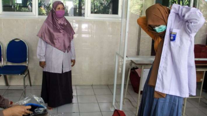 Seorang siswa mencoba seragam sekolah saat mengambil seragam siswa baru di SMA Muhammadiyah 2 (Smamda) Sidoarjo, Jawa Timur, Rabu (10/6/2020).