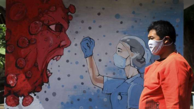 Warga melintas di dekat mural bergambar tenaga medis dan Virus Corona (foto ilustrasi).