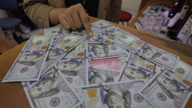 Karyawati menunjukkan mata uang rupiah dan dolar AS di salah satu gerai penukaran mata uang asing di Jakarta.