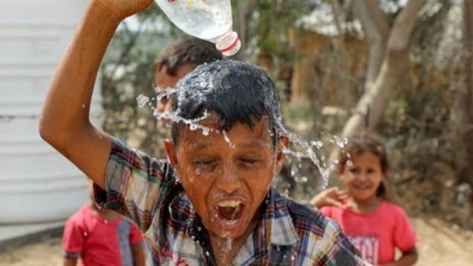 Seorang anak mencoba mendinginkan kepalanya saat gelombang panas di Gaza (BBC Indonesia)