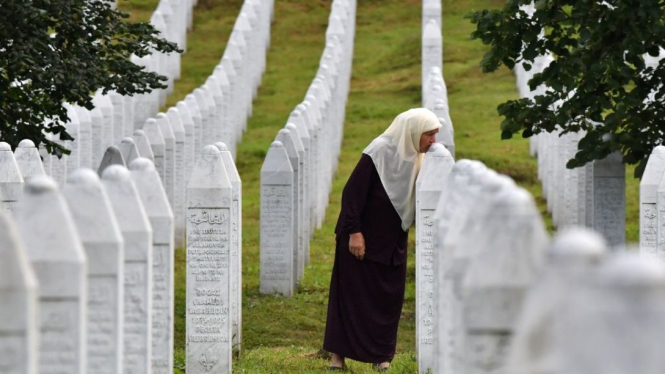 Mejra Djogaz, orang yang selamat dari insiden Srebrenica, mencium makam anaknya.-GETTY IMAGES



