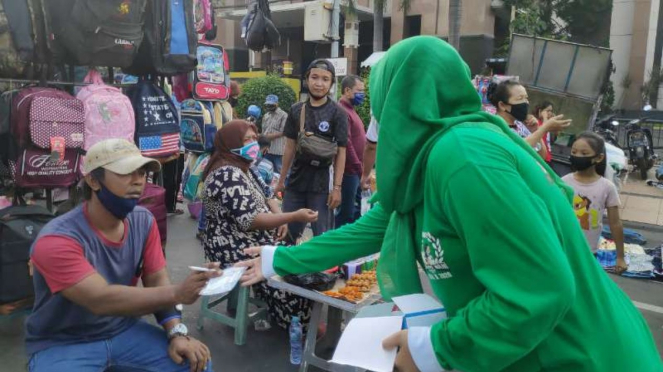 Bonek membagi-bagikan masker di Tugu Pahlawan Surabaya. 