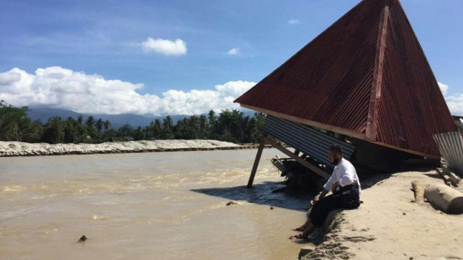 Hamluddin duduk di lokasi yang dulu rumah ibunya, yang kini tertimbun air dan tanah