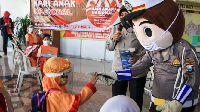 Badut Polisi memberikan masker kepada anak-anak dalam rangka peringatan Hari Anak Nasional di Balai Desa Pepelegi, Waru, Sidoarjo, Jawa Timur, Rabu (22/7/2020). Peringatan Hari Anak Nasional 23 Juli 2020 bertema 