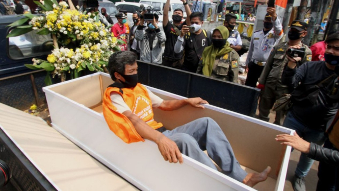 Warga yang tidak memakai masker di Jakarta Timur diberi sanksi masuk ke dalam peti mati pada Rabu (02/09).-AFP/GETTY IMAGES



