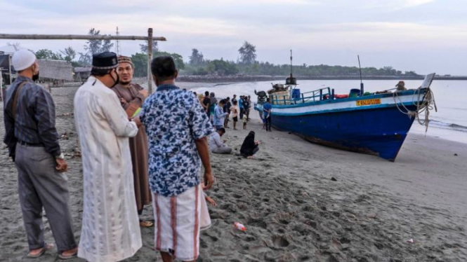Penduduk setempat memeriksa kapal yang membawa ratusan etnis Rohingya yang mendarat di pantai di Lhokseumawe, Aceh.