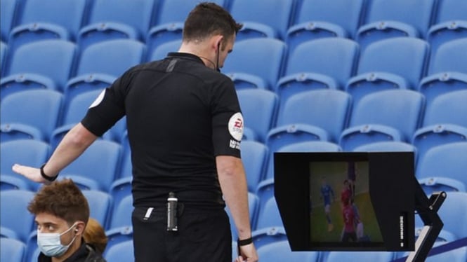 Wasit Brighton vs MU sedang meninjau VAR setelah laga berakhir. 