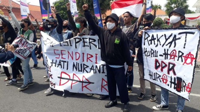 Massa pengunjuk rasa penentang Undang-Undang Omnibus Law Cipta Kerja dengan aparat kepolisian di depan Gedung Negara Grahadi Surabaya, Jawa Timur, pada Kamis, 8 Oktober 2020.