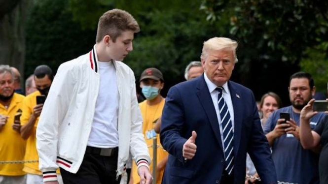 Presiden Amerika Serikat Donald Trump dan putranya Barron berjalan menuju Gedung Putih dari Marine One di Washington, Amerika Serikat, Minggu (16/8/2020).