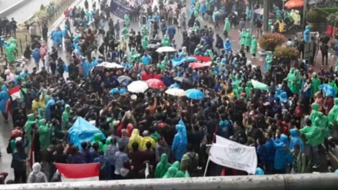 Mahasiswa tetap melanjutkan aksi demonstrasi meski hujan mengguyur.