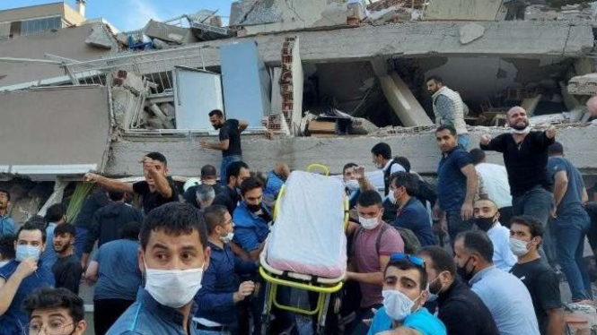 Petugas dan warga mencari korban tertimbun bangunan runtuh akibat gempa Turki.