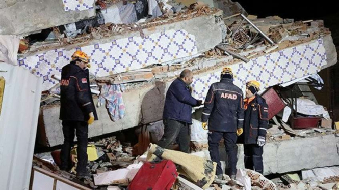 Sejumlah penyelamat berkumpul di sebuah bangunan yang ambruk akibat Gempa Turki.