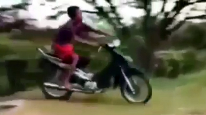 Seorang bocah mengendarai motor Honda Supra