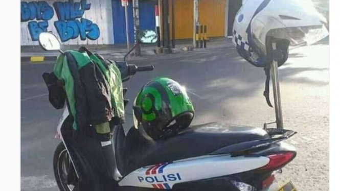 Jaket dan helm ojek online diletakan di motor dinas Polisi.