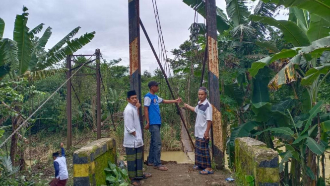 Warga melihat jembatan gantung yang terputus di di Kampung Dukuh, Desa Parungkuj