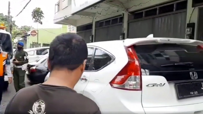 Juru parkir berusaha melindungi mobil yang diparkir dari razia Dishub
