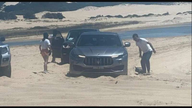 Mobil SUV mewah Maserati nyangkut di pasir pantai.