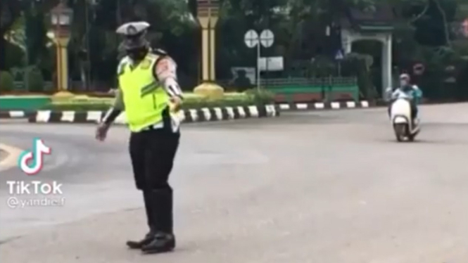 Petugas polisi bantu penyeberang jalan.
