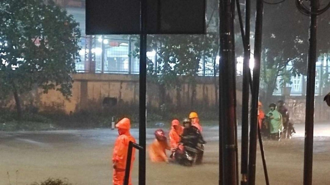 Petugas sedang membantu pengendara motor melintasi banjir di Jakarta Selatan.
