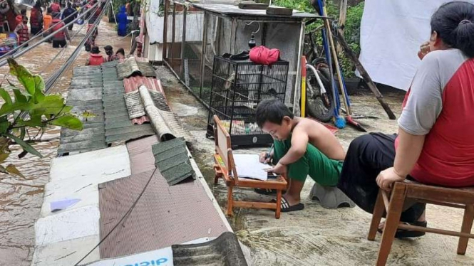 Seorang anak asyik belajar online saat banjir di Cipinang Melayu.